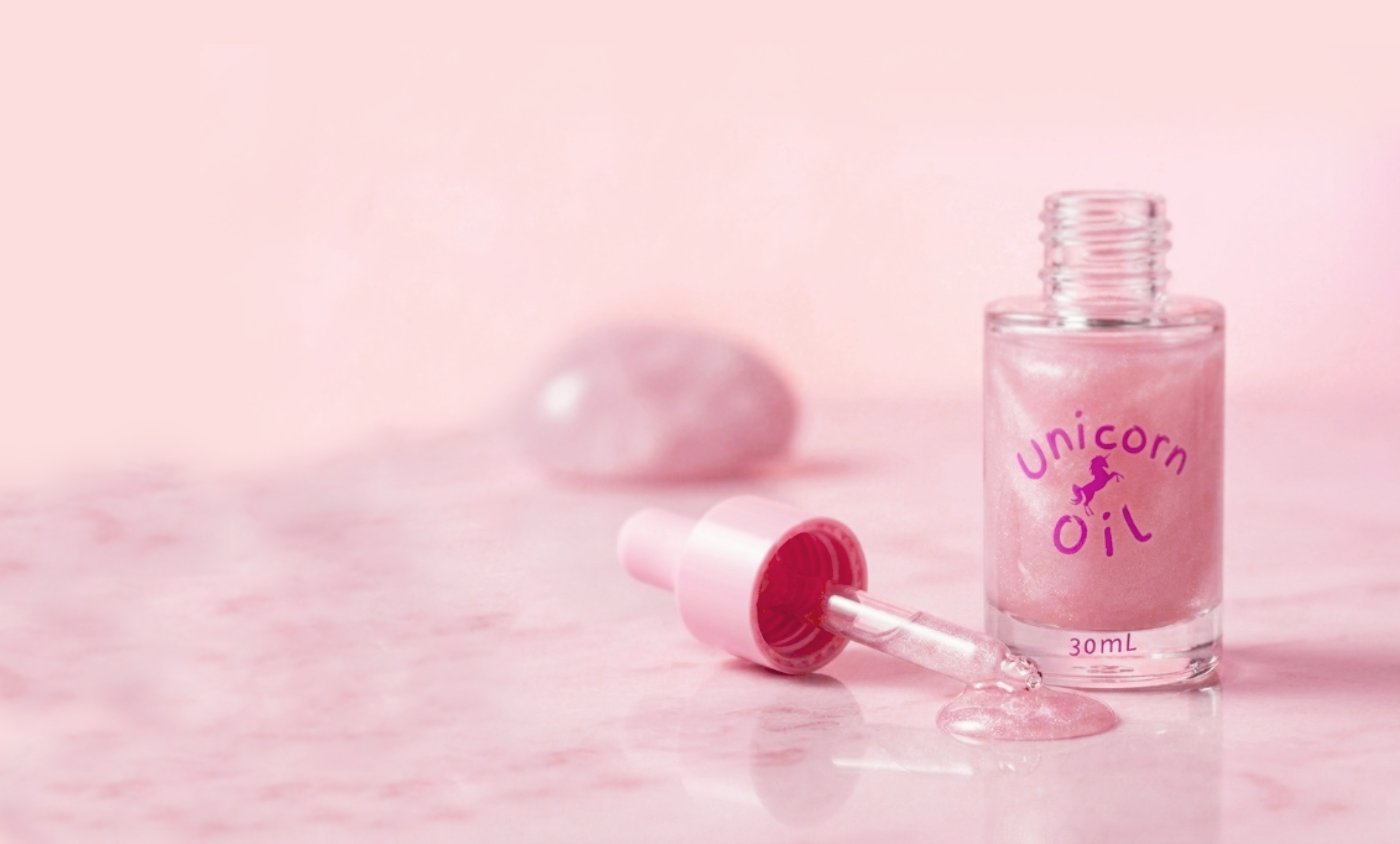 A glass of cuticle oil bottles in pastel pink lighting